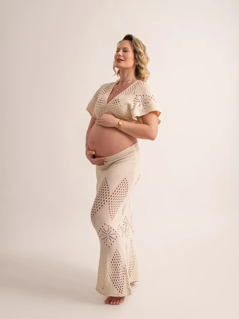 Embarazada con conjunto tejido blanco en el estudio